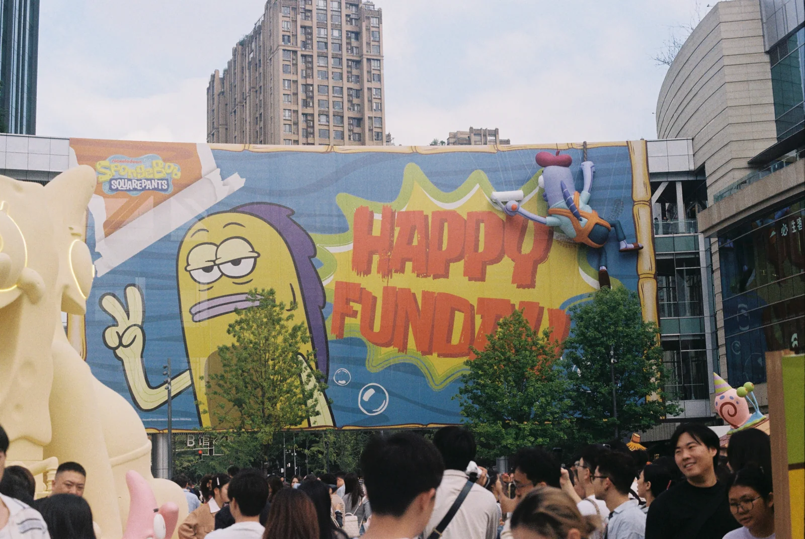 写有 HAPPY FUN 的彩绘墙前聚集的人群