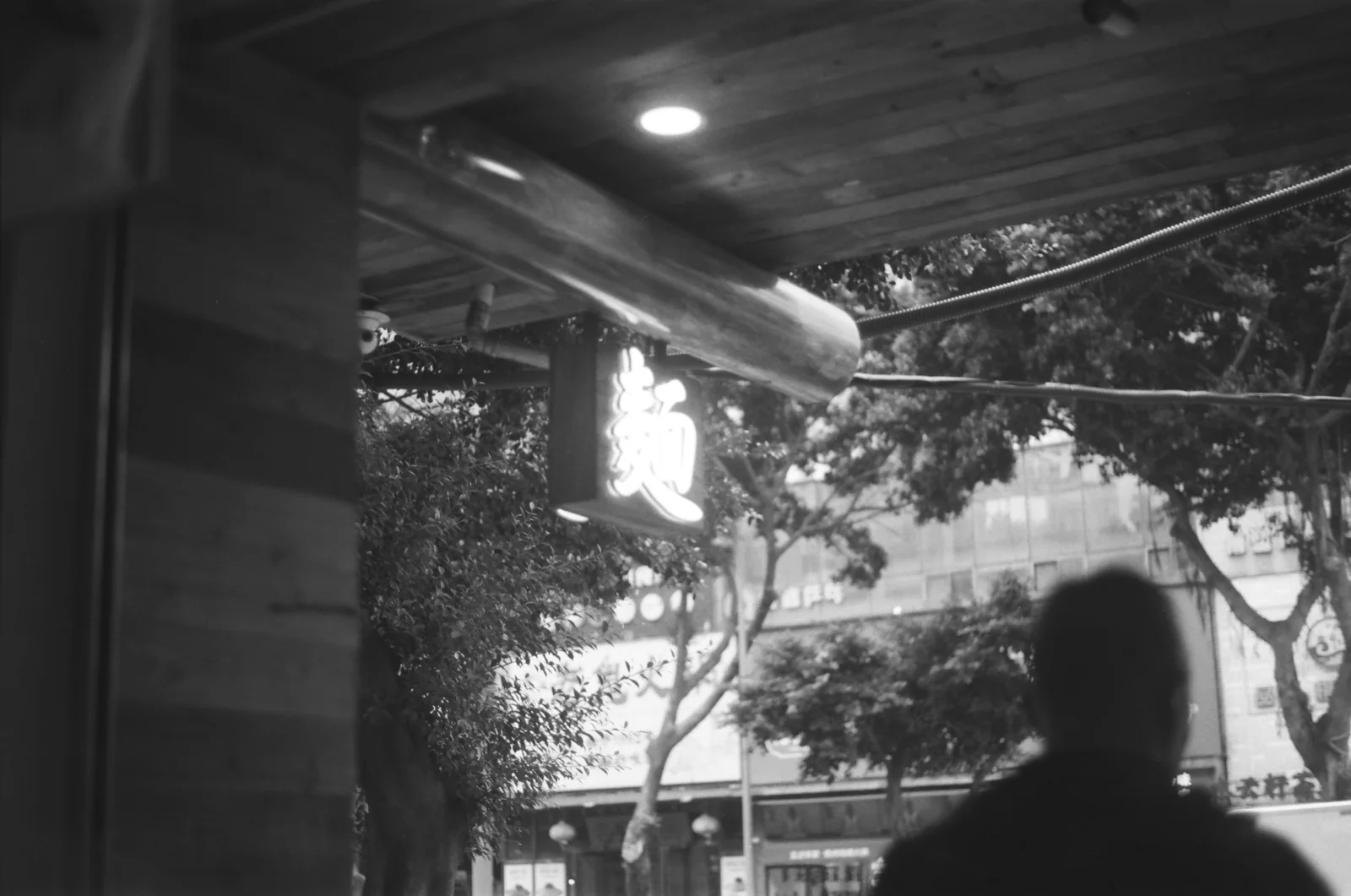 黑白画面里，屋檐下的人影望向街对面