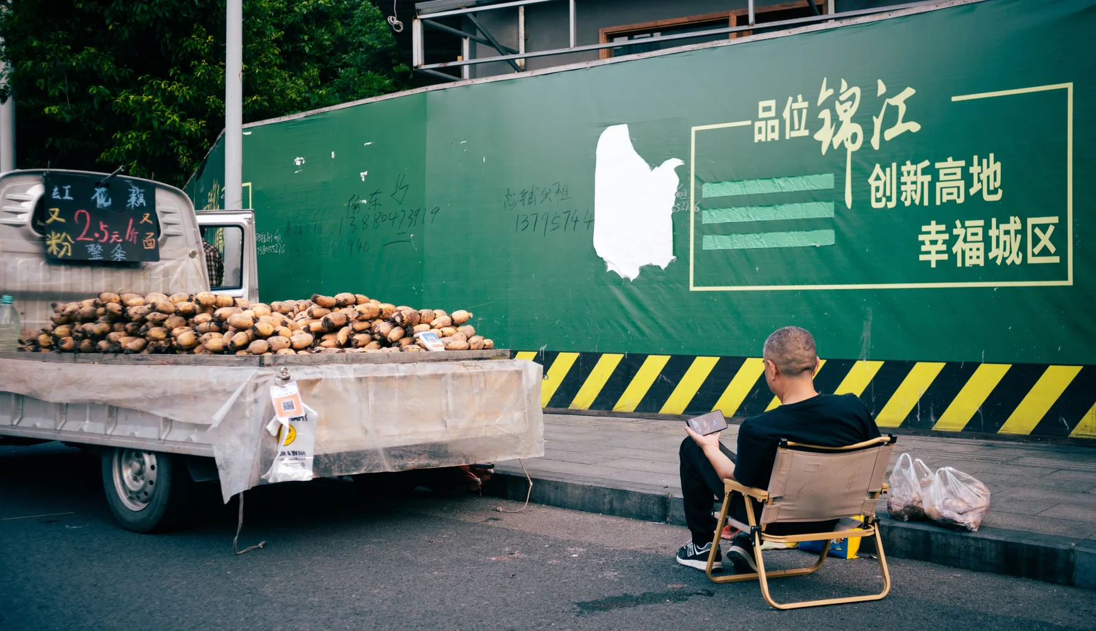 施工围挡前坐着的人与推车