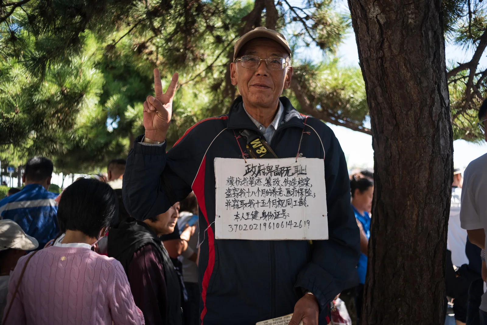 树下坐着的人与胸前悬挂的文字牌