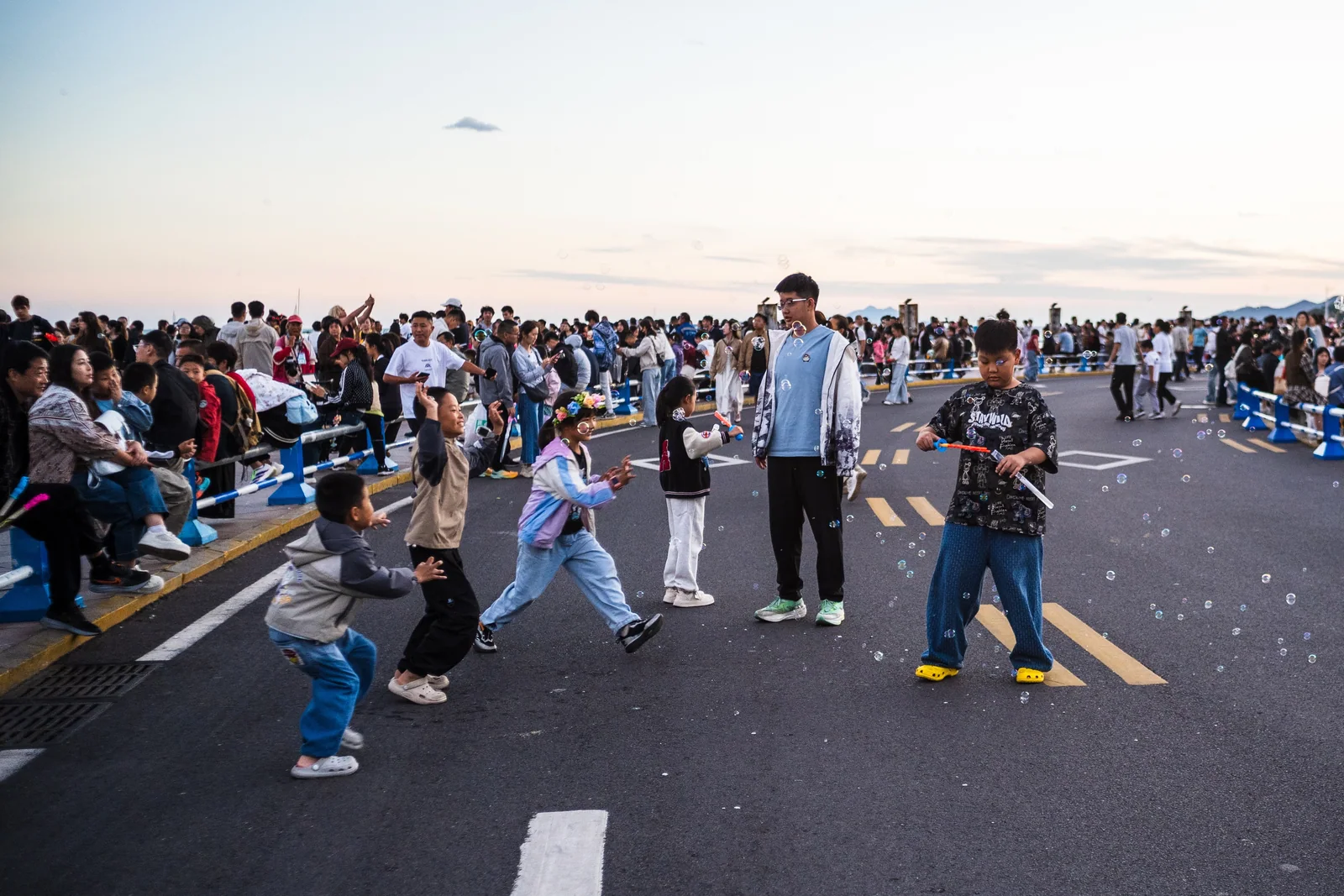 海边道路上，孩子们在人群与肥皂泡之间奔跑