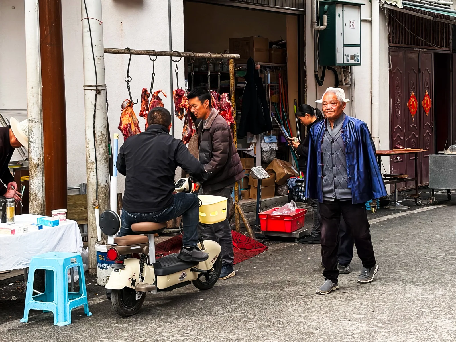 肉铺前的摊位、凳子与路过的老人