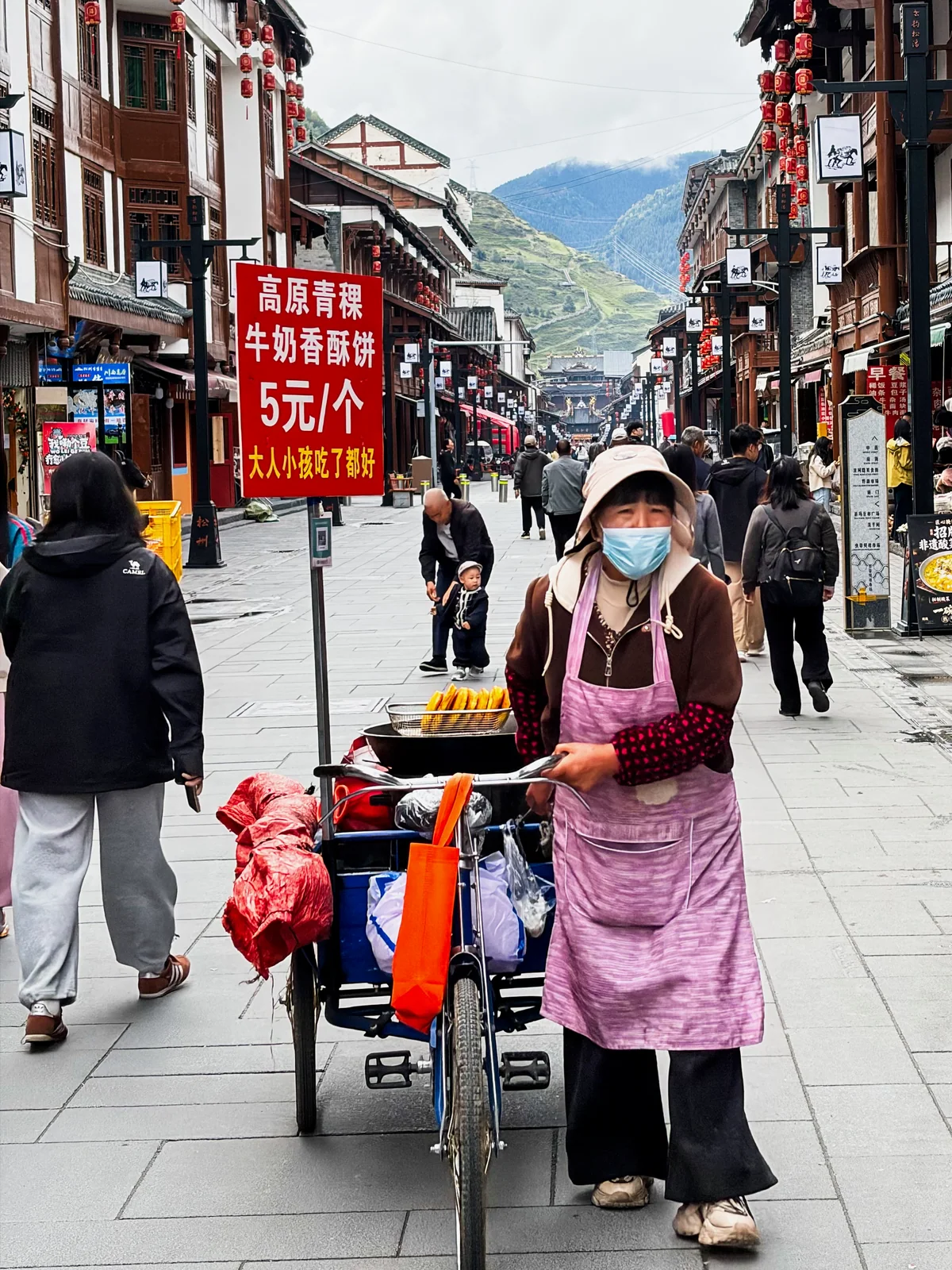 古城街道上戴口罩的摊贩与红色推车