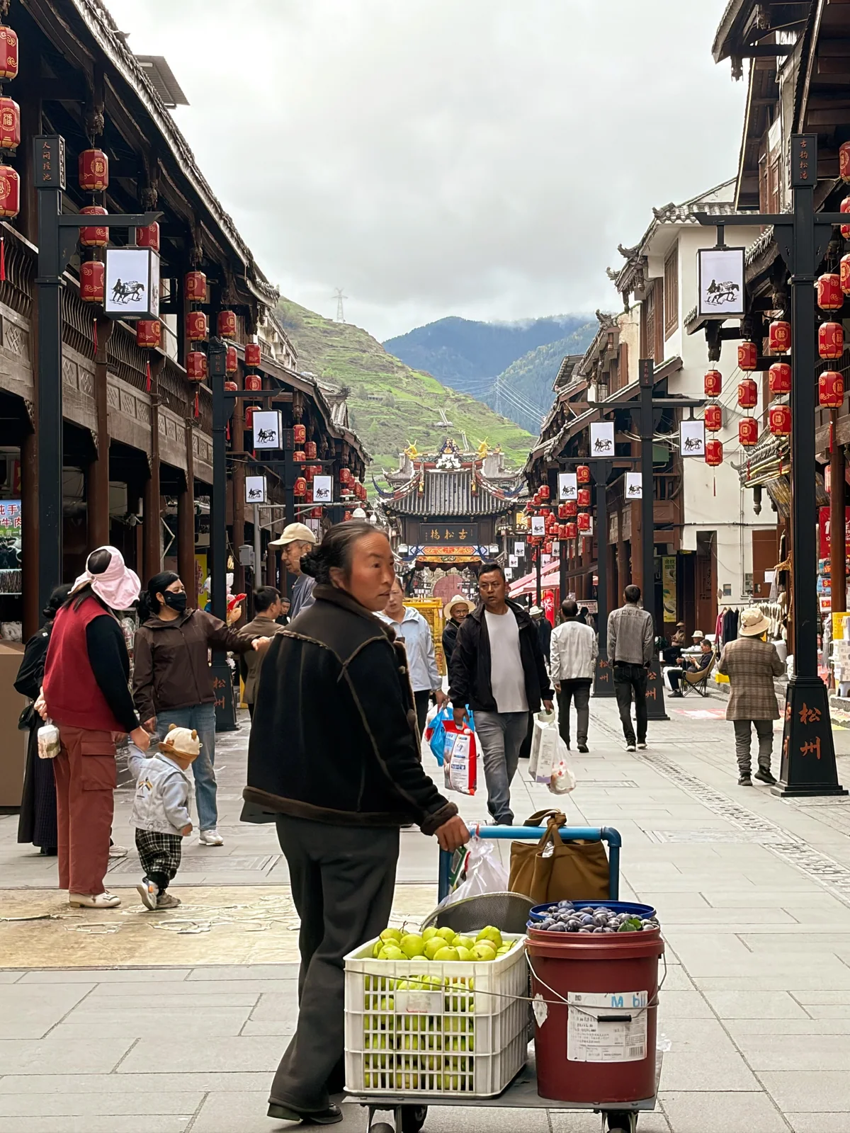远山前的古城街巷与推车行人