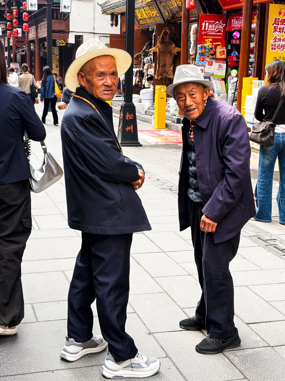两位戴帽子的老人站在街边回望